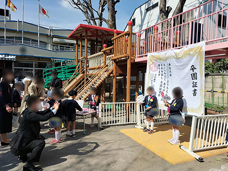 お写真をご提供いただいた学校・幼稚園では、
卒業証書背景幕での写真撮影をお目当てに、長蛇の列が。

「まるでテーマパークのアトラクションと思うような20～30分位待ちそうな長い列でした！」
とのお話もお伺いしました。
またスタッフがお伺いした学校では、
校庭の端に設置した卒業証書背景幕の前には、
なんと40～50分位待つのではないかと思うほど、
かなり長い列が校庭中央にまでに達していることもありました。